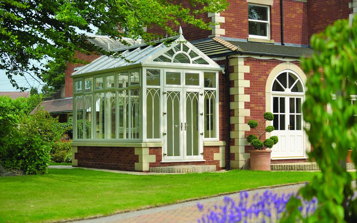 Glazed conservatory with a pitched roof attached to a brick house
