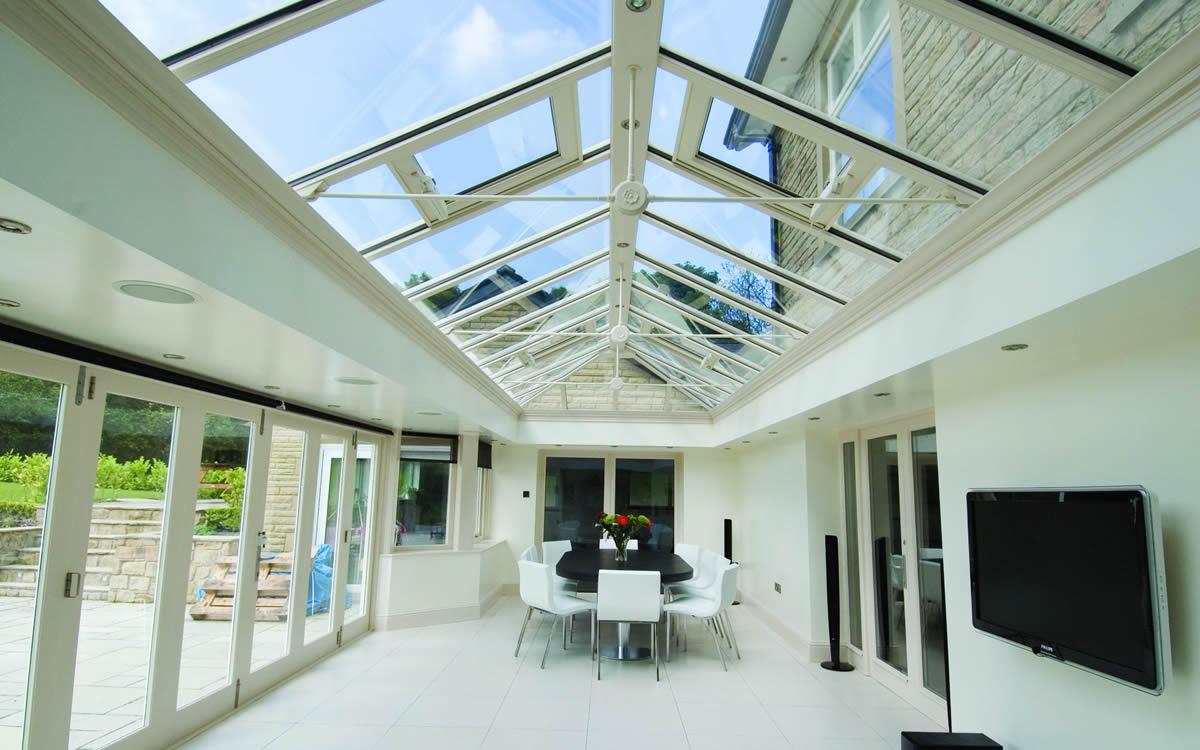 Bright orangery interior with a glazed roof lantern and garden views
