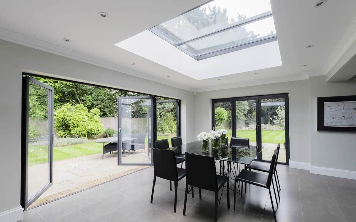 Open-plan dining room with aluminium bifolding doors folded back onto a garden